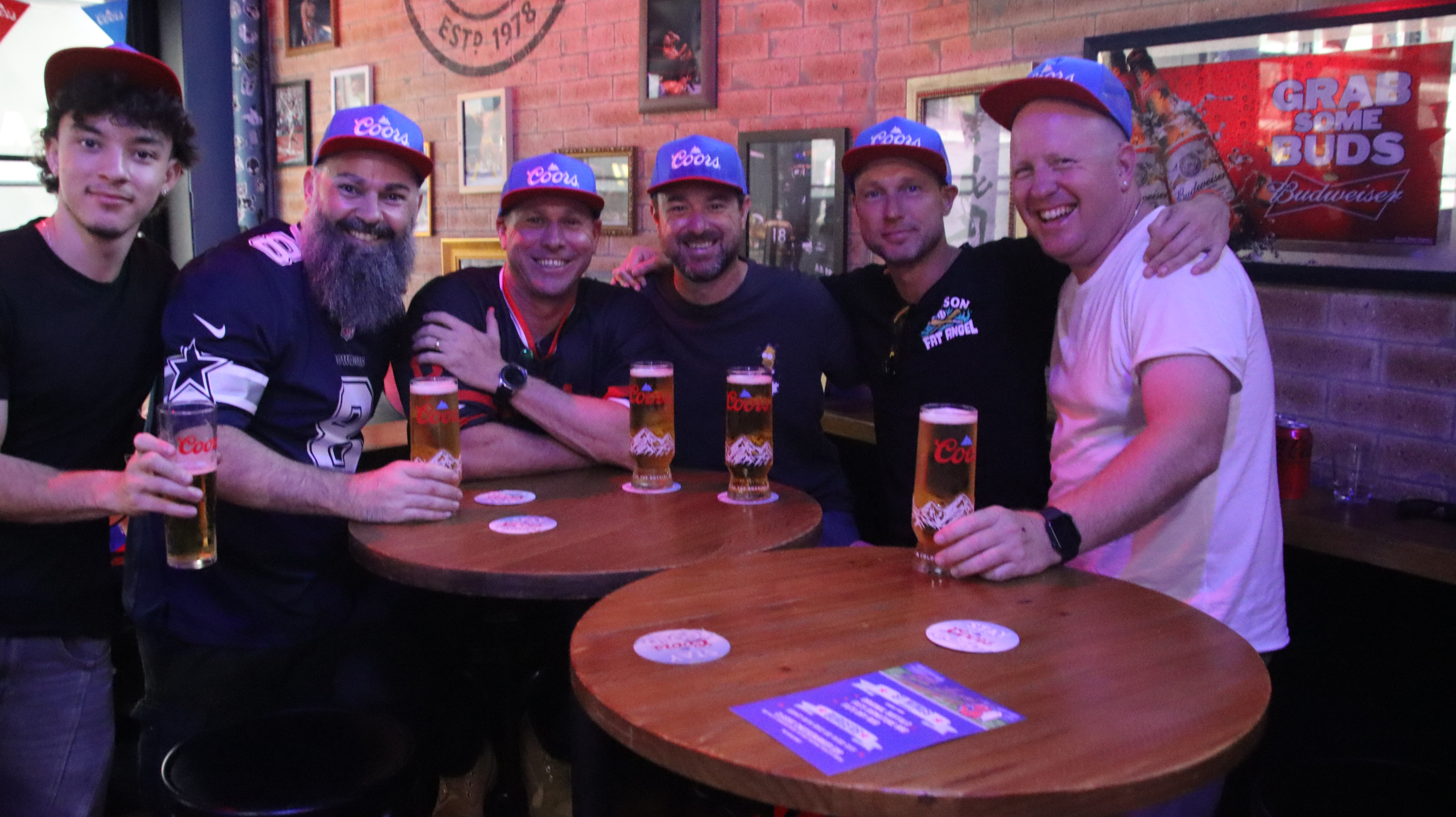 Mates raising Coors beers around the table